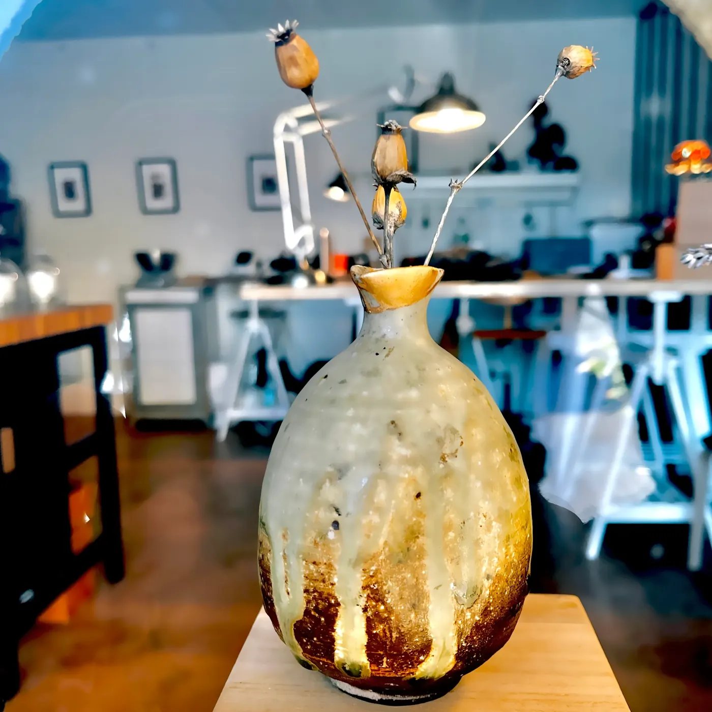 Le tokkuri restauré, le bord du col entièrement doré, les coulures de son émail visibles sur la panse ; quelques fleurs séchées dans le col.