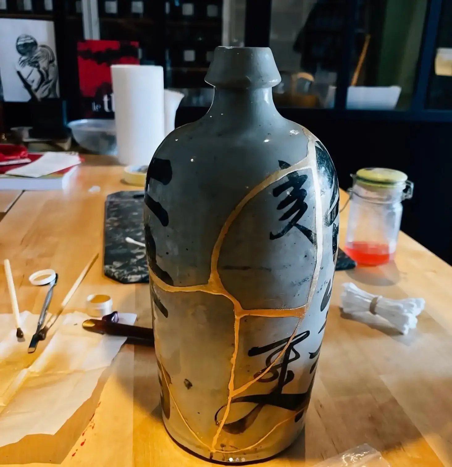 Établi de l'atelier : bouteille à saké en cours de restauration et outils