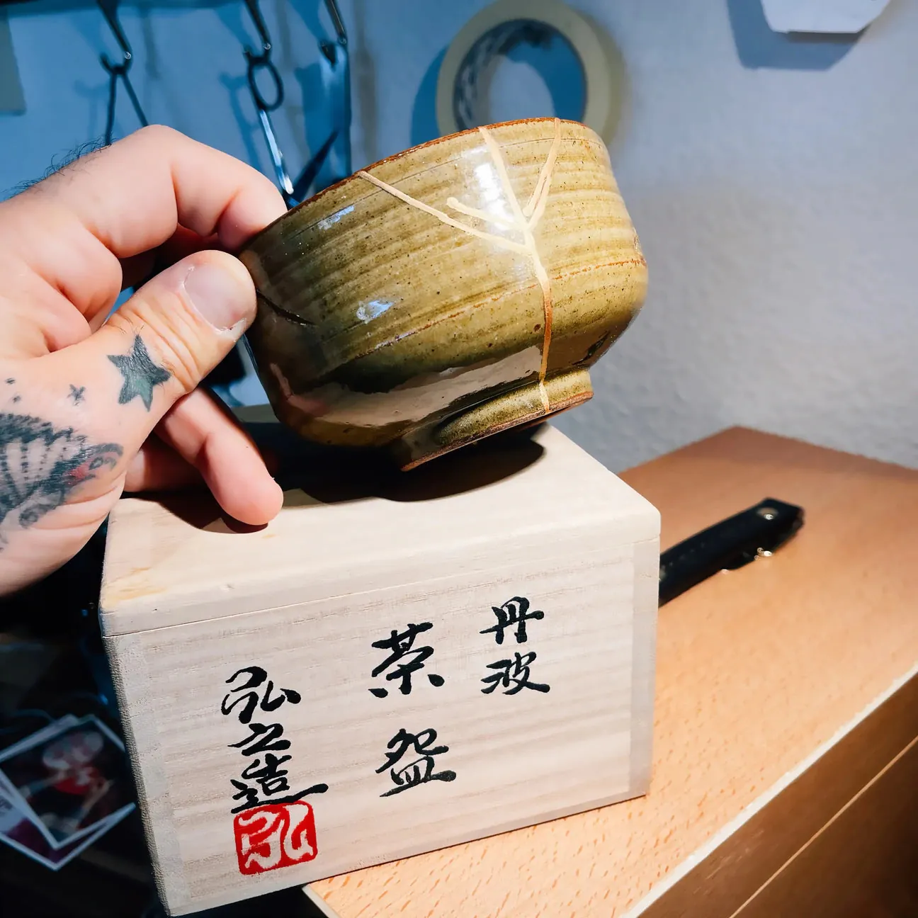 Chawan restauré à l'or tenu au-dessus de sa boîte